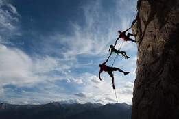 mountain climbers rappelling in a row